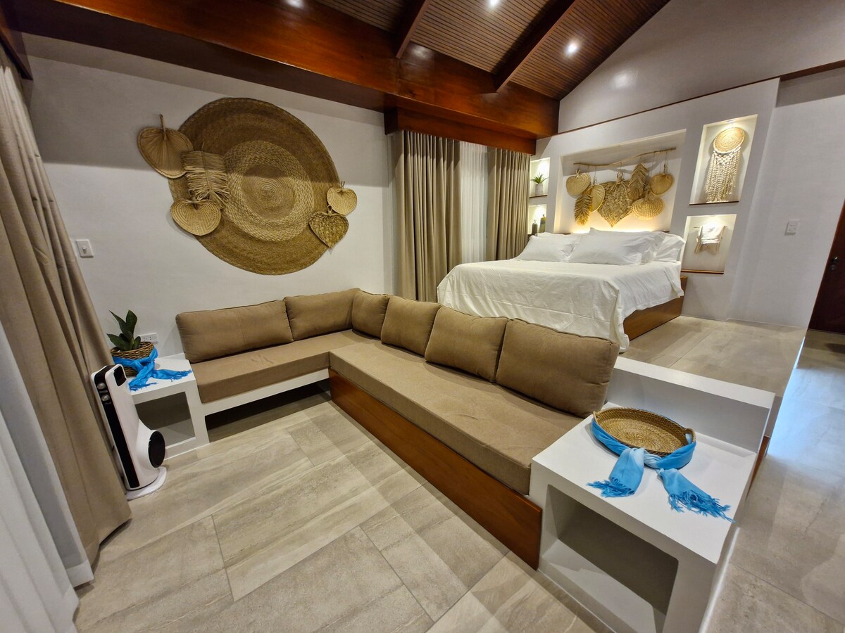 Full villa interior with sectional sofa, king bed, and artisan wall decor